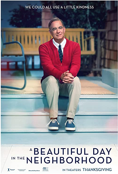 Poster for A Beautiful Day in the Neighborhood, featuring a white man with gray hair who is sitting on the steps of a porch. He wears a red cardigan sweater, a blue patterned tie, and blue sneakers.