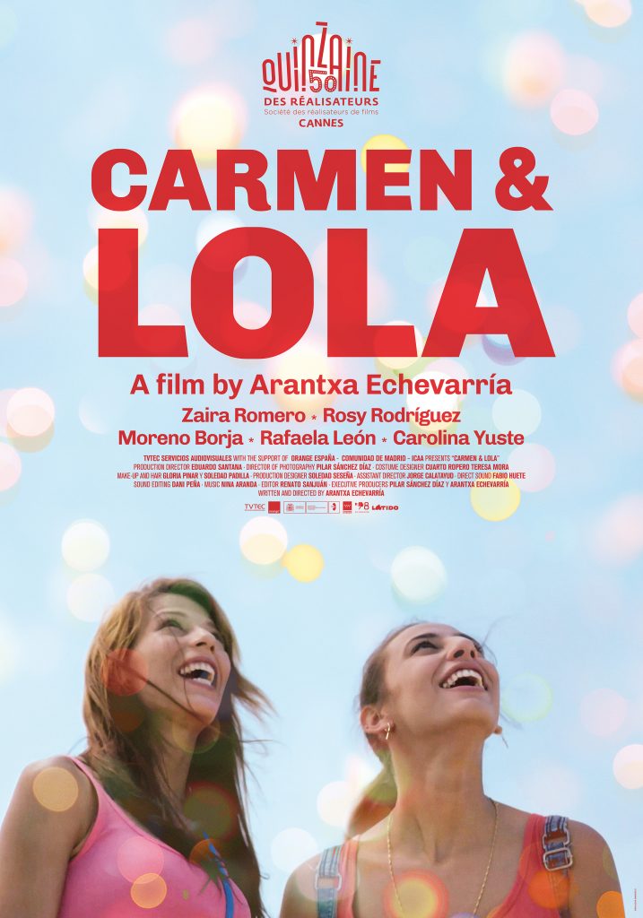 Poster for Carmen & Lola, dominated by the film's title in red capital letters. At the bottom of the poster, two young women with wind-swept hair look upward at a sky full of colorful round lights.