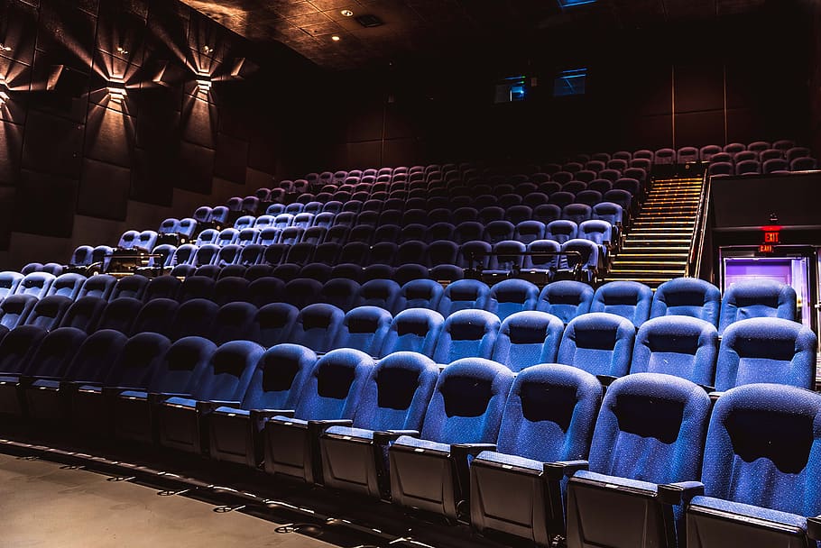 Photograph of an empty movie theater with many rows of blue stadium-style seats.